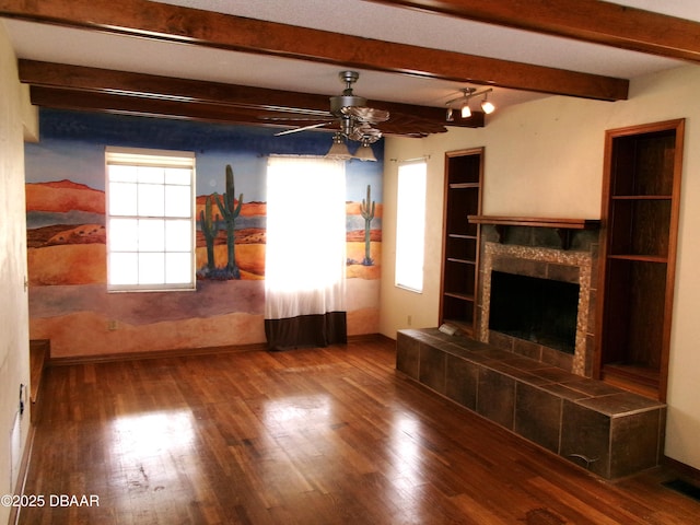 unfurnished living room with beamed ceiling, hardwood / wood-style floors, a fireplace, and ceiling fan