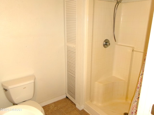 bathroom with a tile shower, tile patterned floors, and toilet