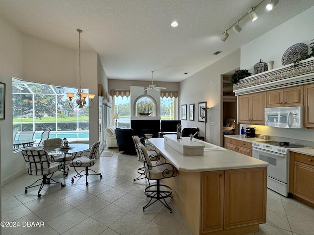 kitchen with white appliances, a chandelier, a breakfast bar, a center island, and decorative light fixtures