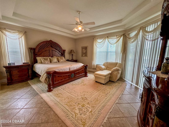 4 Lakewood Dr, Ormond Beach, FL 32174 - bedroom featuring a tray ceiling, multiple windows, light tile patterned flooring, and a ceiling fan