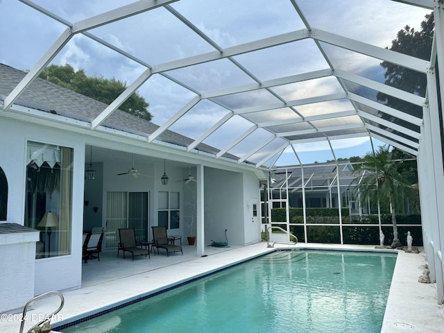 view of swimming pool featuring ceiling fan, glass enclosure, and a patio area