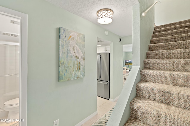 staircase with a textured ceiling and tile patterned flooring