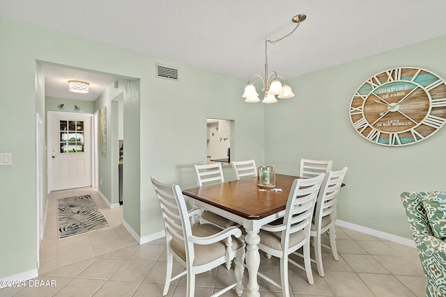 tiled dining space featuring a textured ceiling and a notable chandelier