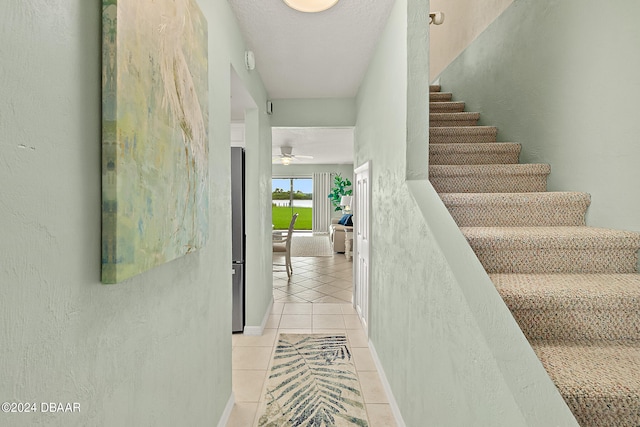 staircase featuring tile patterned flooring and ceiling fan