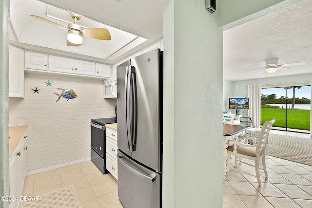 kitchen with white cabinetry, ceiling fan, light tile patterned floors, stainless steel fridge, and black electric range oven