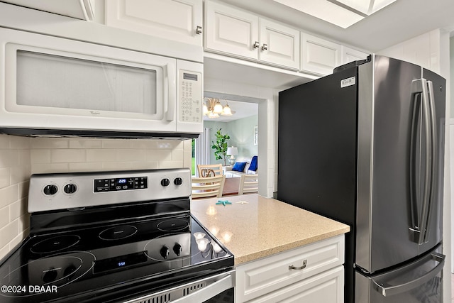 kitchen featuring white cabinets, an inviting chandelier, backsplash, and appliances with stainless steel finishes