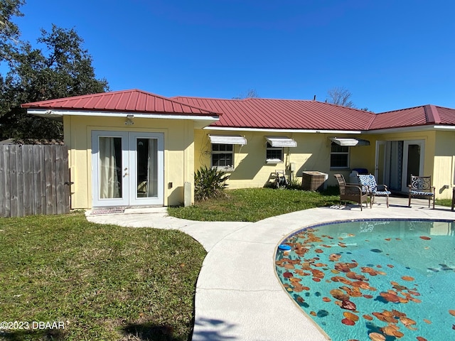 rear view of property with french doors, a patio, a yard, and a fenced in pool