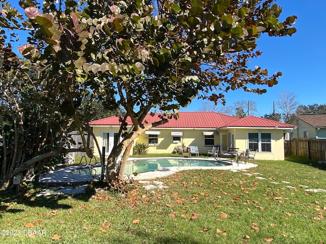 rear view of property with a patio, a fenced in pool, and a yard