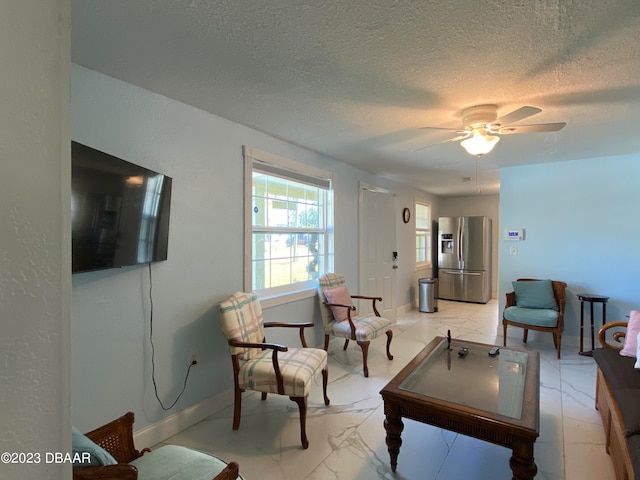 living room with ceiling fan and a textured ceiling