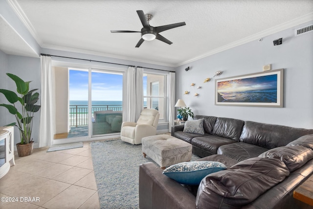 tiled living room with ceiling fan, a water view, a textured ceiling, and ornamental molding