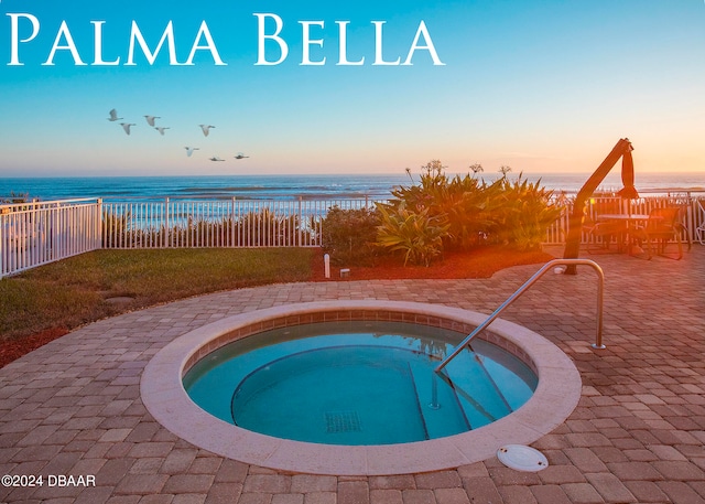 pool at dusk featuring a water view and a hot tub