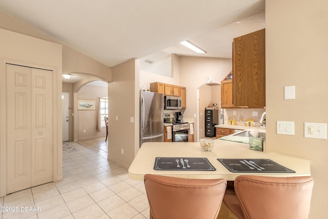 1692 Old Tomoka Rd Unit W, Ormond Beach, FL 32174 - kitchen featuring stainless steel appliances, arched walkways, a sink, a peninsula, and light tile patterned floors