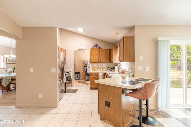 1692 Old Tomoka Rd Unit W, Ormond Beach, FL 32174 - kitchen featuring a sink, brown cabinets, a peninsula, light countertops, and arched walkways