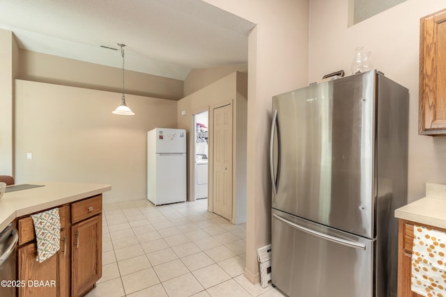 1692 Old Tomoka Rd Unit W, Ormond Beach, FL 32174 - kitchen featuring freestanding refrigerator, washer / dryer, brown cabinets, lofted ceiling, and light countertops