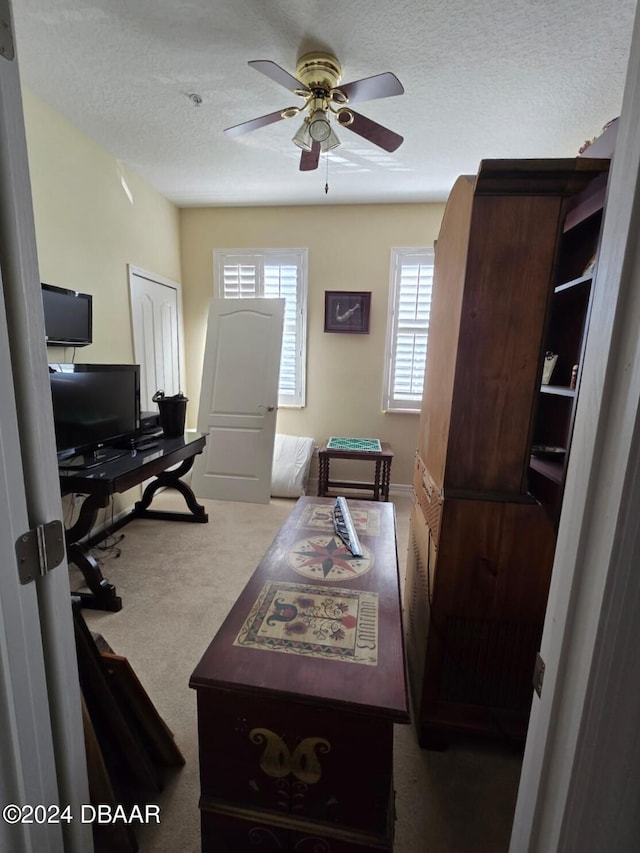 carpeted office space featuring a textured ceiling and ceiling fan