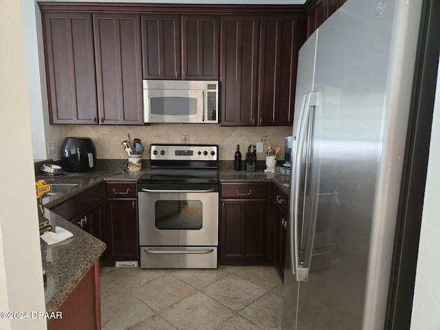 kitchen featuring dark stone countertops, backsplash, sink, and stainless steel appliances