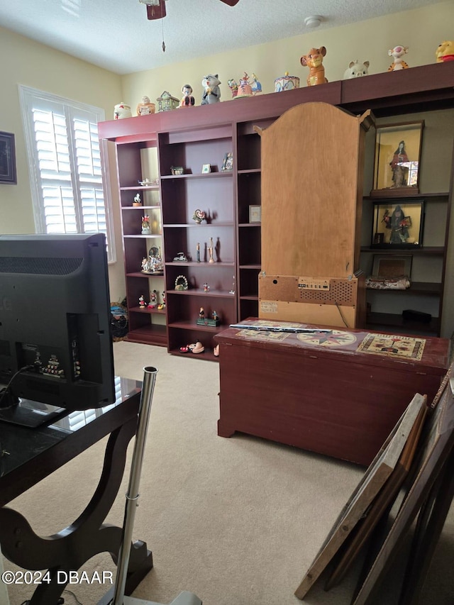 carpeted home office with a textured ceiling and ceiling fan