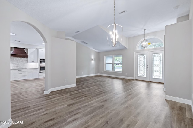 7 Traceway Ct, Ormond Beach, FL 32174 - unfurnished living room featuring a chandelier, light wood-style floors, arched walkways, and lofted ceiling