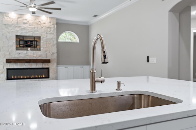 7 Traceway Ct, Ormond Beach, FL 32174 - kitchen view of a warm lit fireplace, light stone counters, a ceiling fan, arched walkways, and ornamental molding