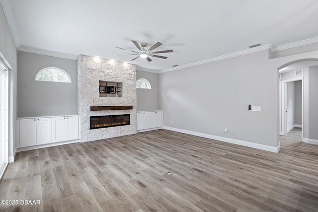 7 Traceway Ct, Ormond Beach, FL 32174 - unfurnished living room featuring a ceiling fan, arched walkways, a stone fireplace, crown molding, and wood finished floors