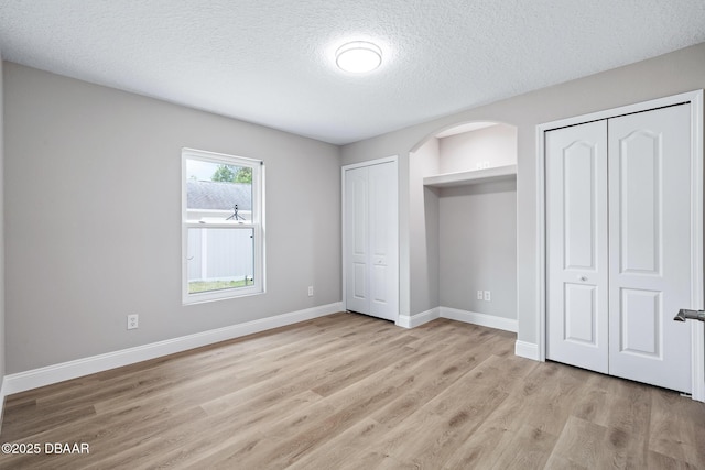 7 Traceway Ct, Ormond Beach, FL 32174 - unfurnished bedroom with two closets, light wood-style flooring, and a textured ceiling