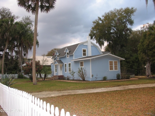 view of front of home with a front lawn, fence, and a gambrel roof