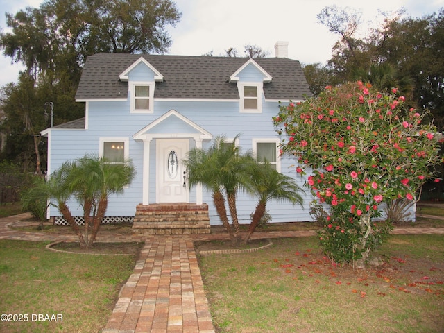 view of front of house with entry steps, roof with shingles, and a front yard