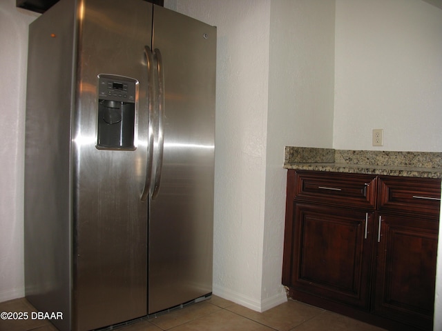 details featuring baseboards, light stone counters, and stainless steel fridge with ice dispenser