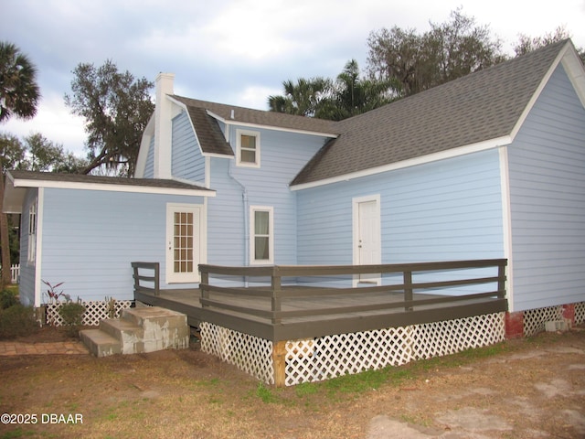 rear view of property featuring a deck, roof with shingles, a chimney, and a gambrel roof