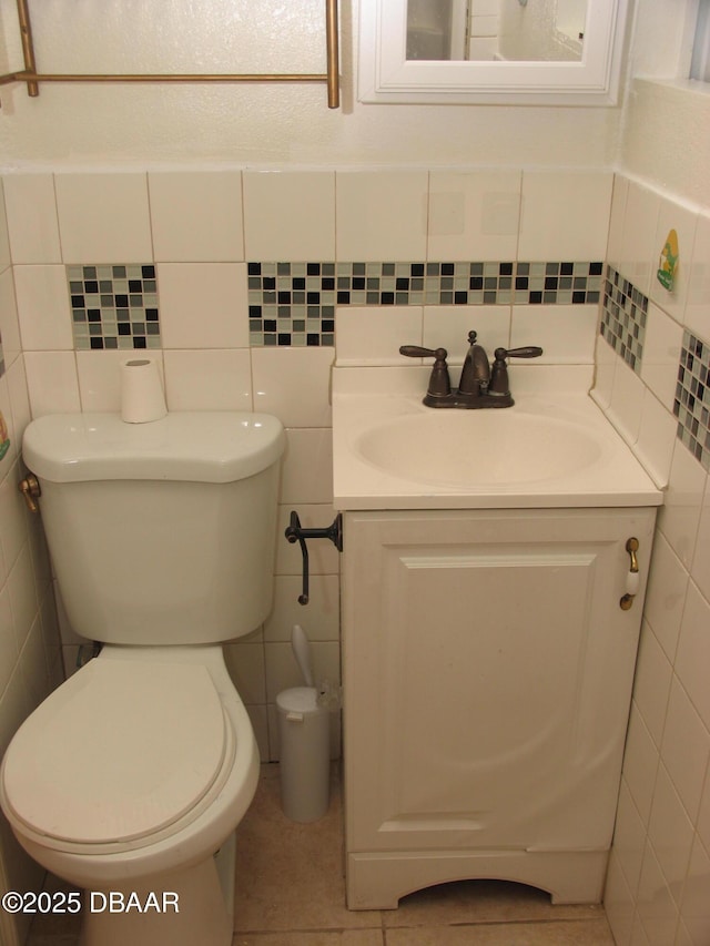 half bath featuring tile walls, vanity, toilet, and tile patterned floors