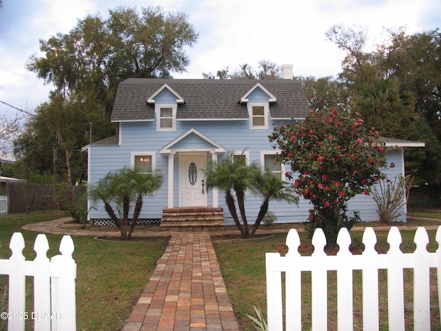 view of front of home with entry steps, a shingled roof, a front lawn, and fence