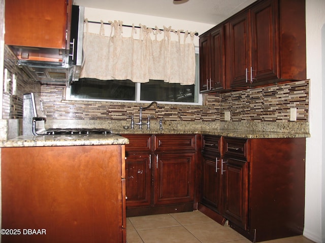 kitchen with light stone counters, dark brown cabinets, and tasteful backsplash