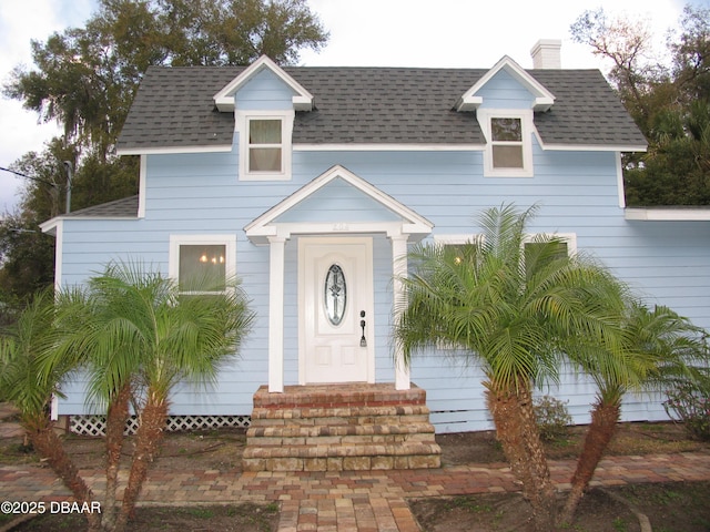 view of front of home with entry steps, roof with shingles, and a chimney