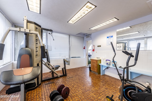 exercise room with tile walls and a healthy amount of sunlight