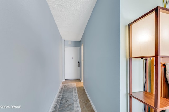 hallway featuring light tile patterned floors and a textured ceiling