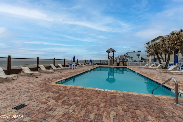 view of pool with a patio area and a water view