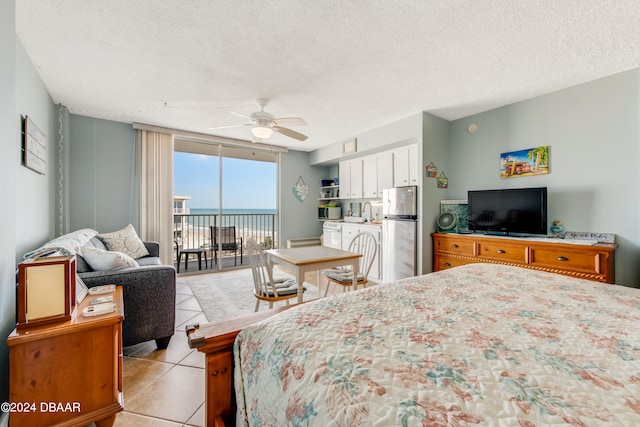 bedroom featuring access to exterior, stainless steel fridge, a textured ceiling, ceiling fan, and light tile patterned flooring