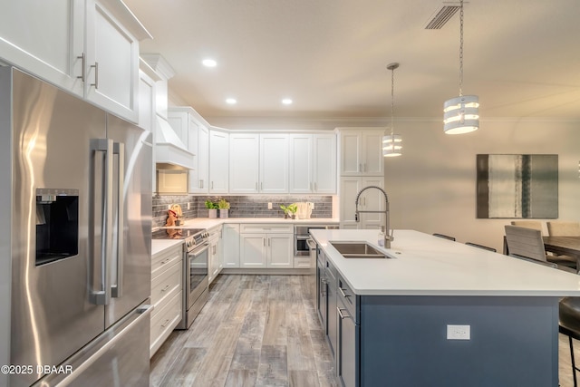 kitchen with sink, white cabinetry, decorative light fixtures, light hardwood / wood-style flooring, and stainless steel appliances