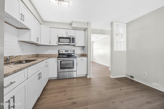656 Winchester St, Daytona Beach, FL 32114 - kitchen with white cabinets, appliances with stainless steel finishes, a sink, dark wood-type flooring, and backsplash