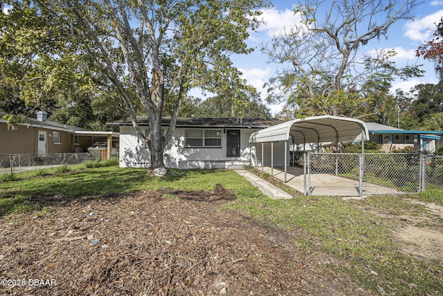 656 Winchester St, Daytona Beach, FL 32114 - back of house featuring a lawn, fence, and a carport