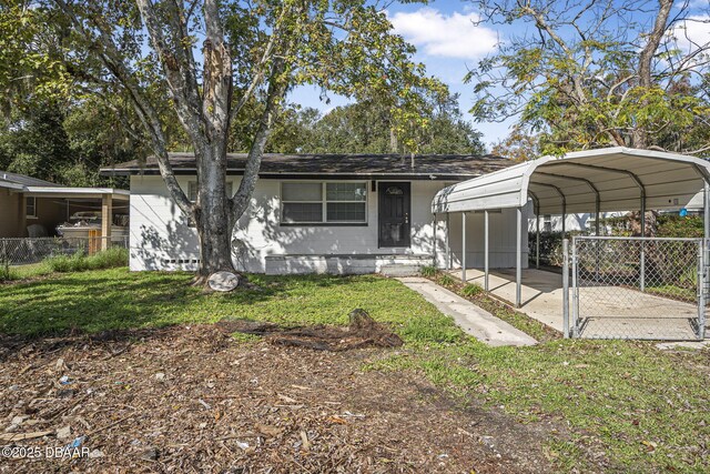 656 Winchester St, Daytona Beach, FL 32114 - view of front facade with concrete block siding, fence, a front yard, and a carport