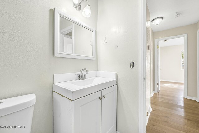 656 Winchester St, Daytona Beach, FL 32114 - bathroom with vanity, a textured wall, wood finished floors, toilet, and baseboards