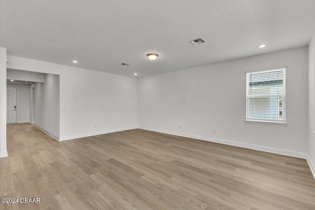 unfurnished room featuring light hardwood / wood-style flooring and a textured ceiling