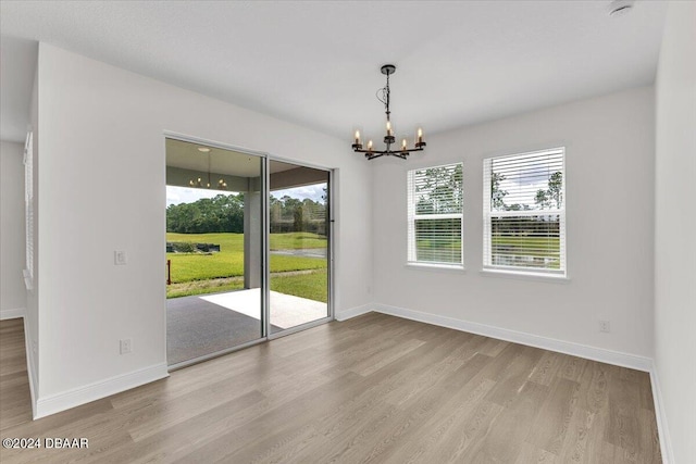 empty room with light hardwood / wood-style floors and a chandelier