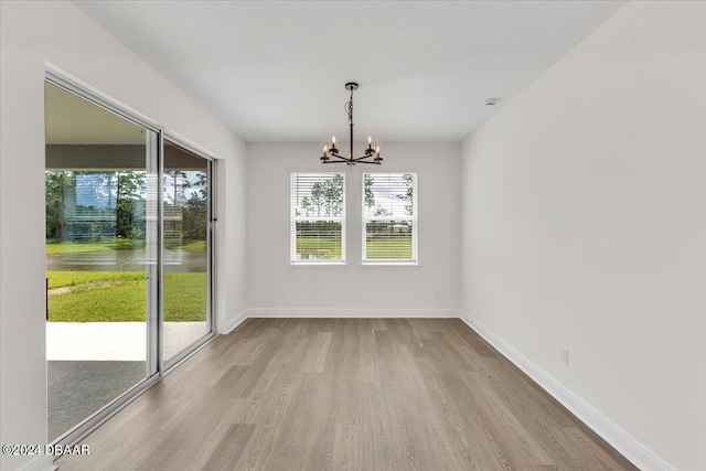 unfurnished dining area with a chandelier and light hardwood / wood-style flooring