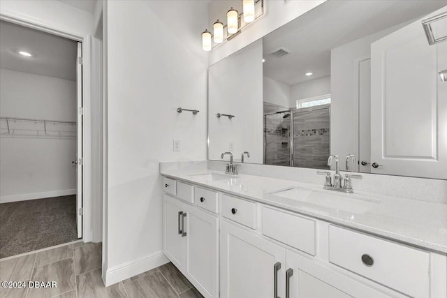 bathroom featuring a shower with door and vanity