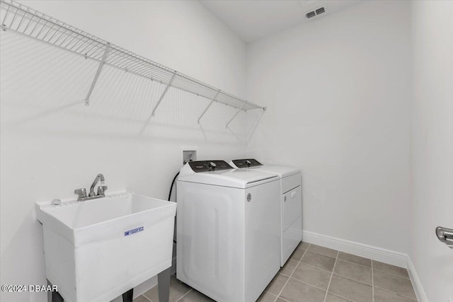 clothes washing area featuring washer and clothes dryer, light tile patterned floors, and sink