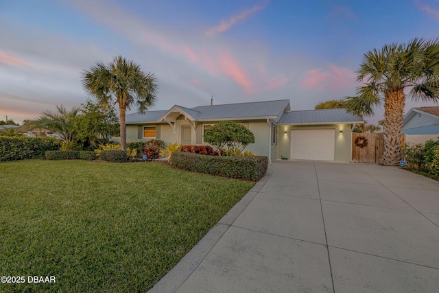 single story home featuring a garage and a yard