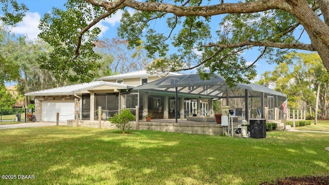 rear view of house with a garage, glass enclosure, and a lawn