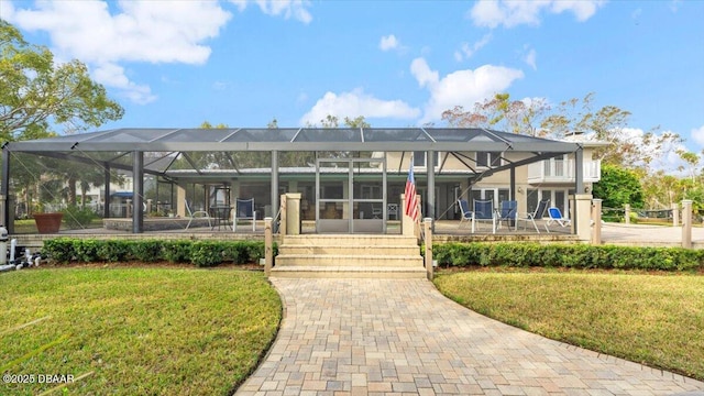 back of property featuring a lanai and a lawn